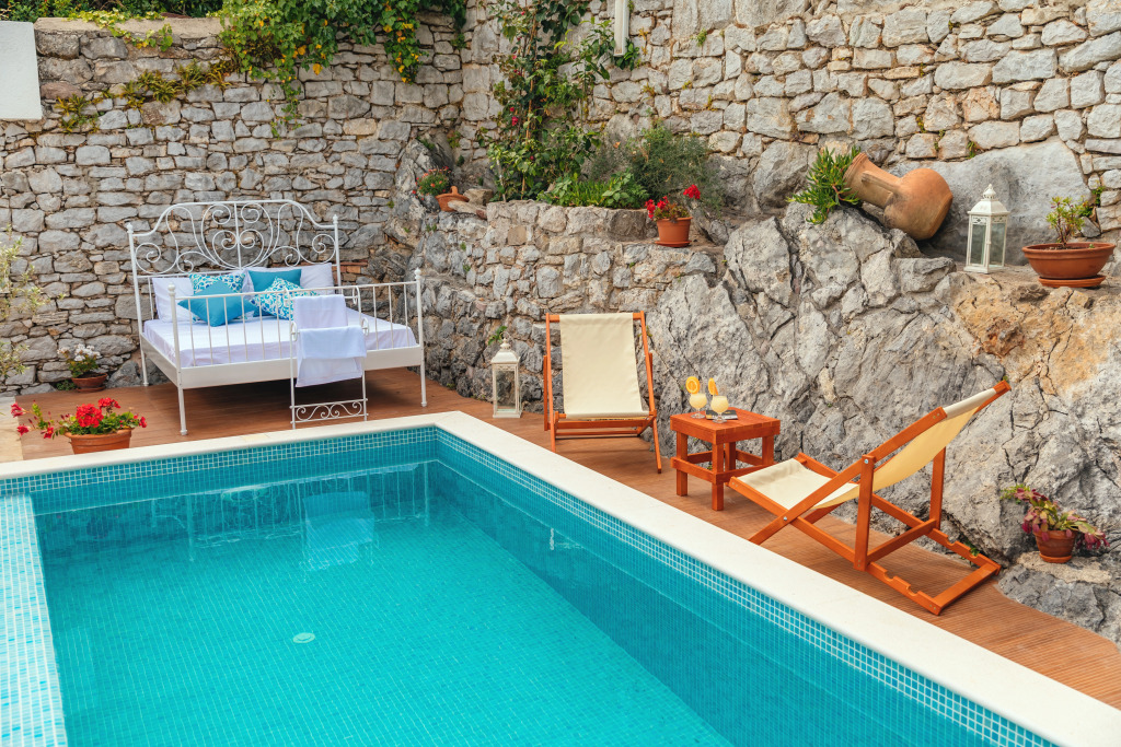 Pool tucked against the old stone wall, daybed and deck chairs