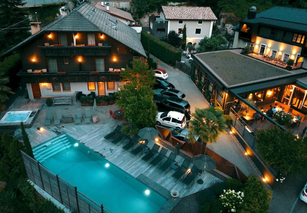 Eggentaler from above at dusk — the pool lit turquoise, the chalet, the cars, the valley