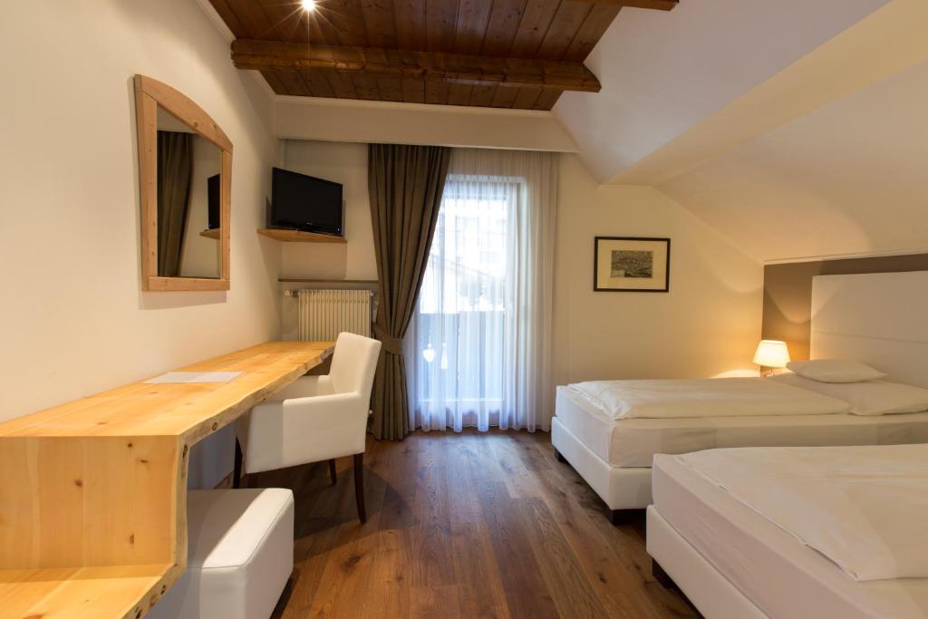 The room — wood-beam ceiling, hardwood floor, twin beds, the desk made from a single live-edge plank