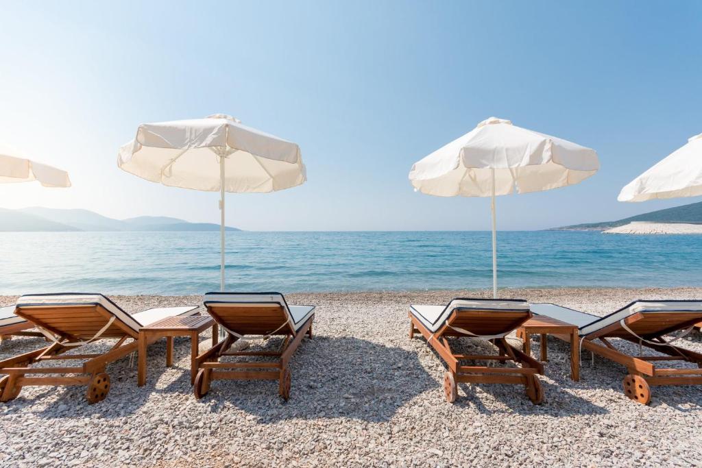 Pebble cove with loungers and umbrellas, mountains in the haze