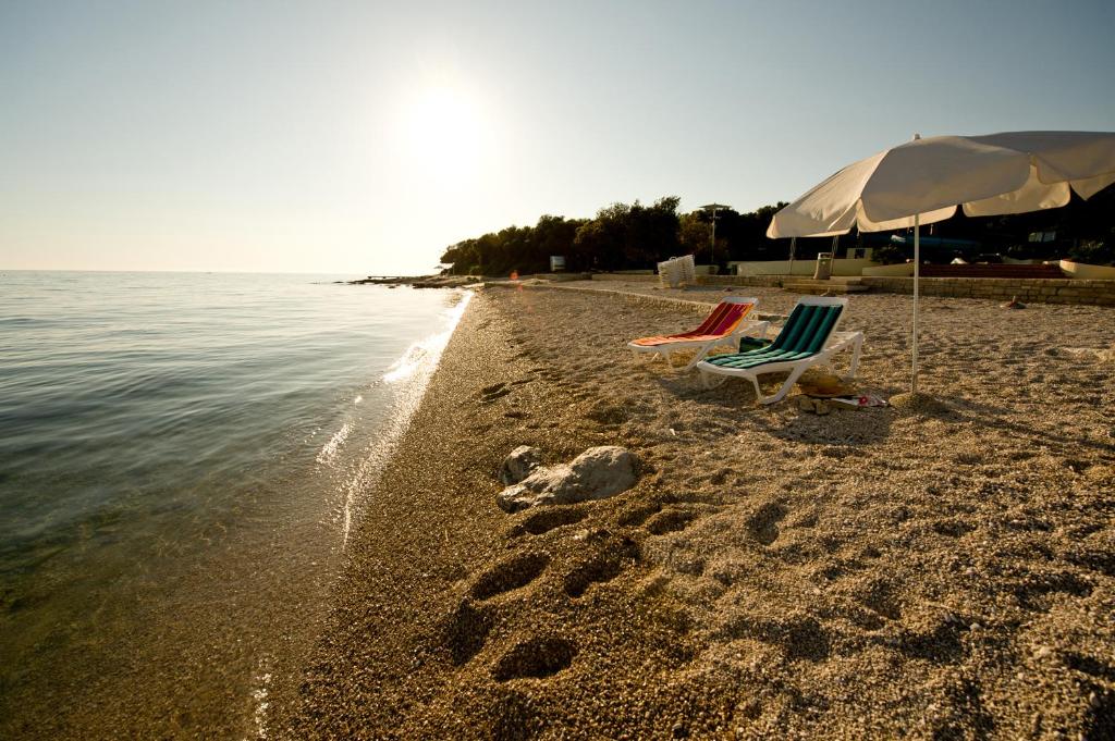 The beach in the morning — pebble shore, calm sea, an umbrella