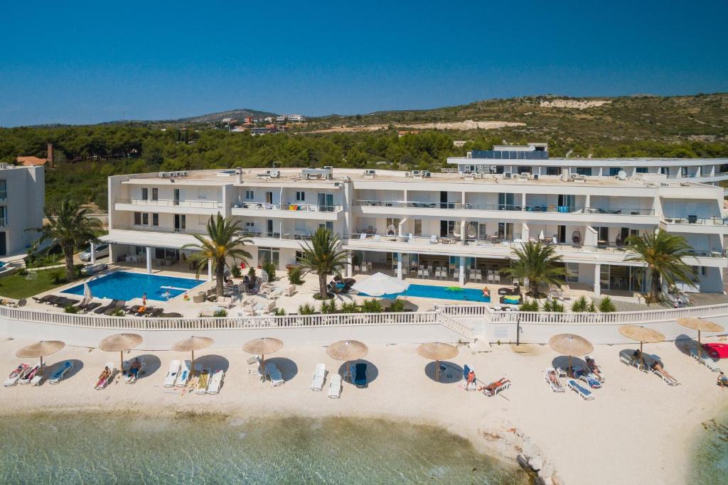 Resort facade above the beach — twin pools, sunshades on the sand, turquoise water